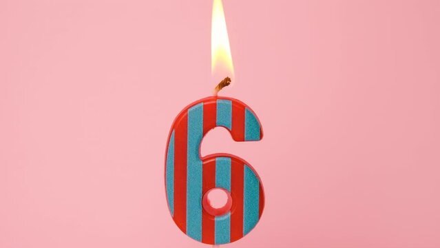 Six years Anniversary video banner with Burning stripped red and blue number six candle on light pink background. 4K resolution happy birthday banner.