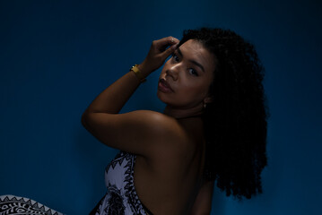 Portrait of beautiful young woman, with curly hair, in low light looking at the camera.