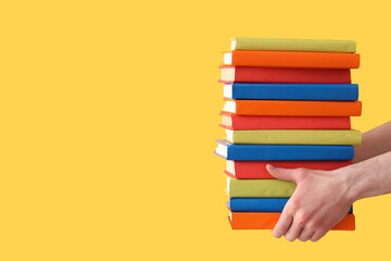 Hands holding books on yellow background