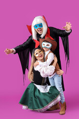 Happy family in costumes and carnival masks on purple background