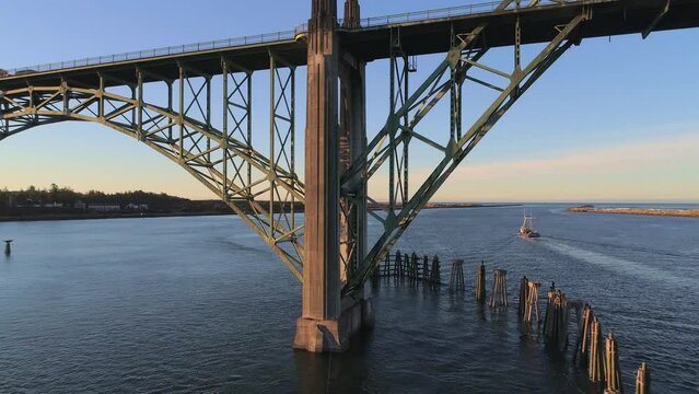 Aerial Drone Video- Yaquina Bay Bridge Sunrise- Newport Oregon-  South support slow dolly out w fishing boat in background V08