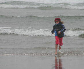 red haired freckled girl child studying jellyfish on beach in Oregon