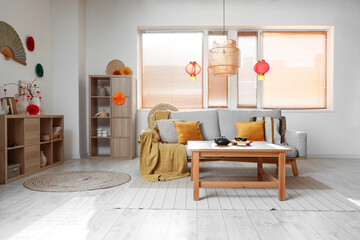 Interior of festive living room with tea set on table, grey sofa and traditional Chinese...