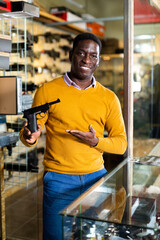 African american man chooses and buys pistol at a gun store