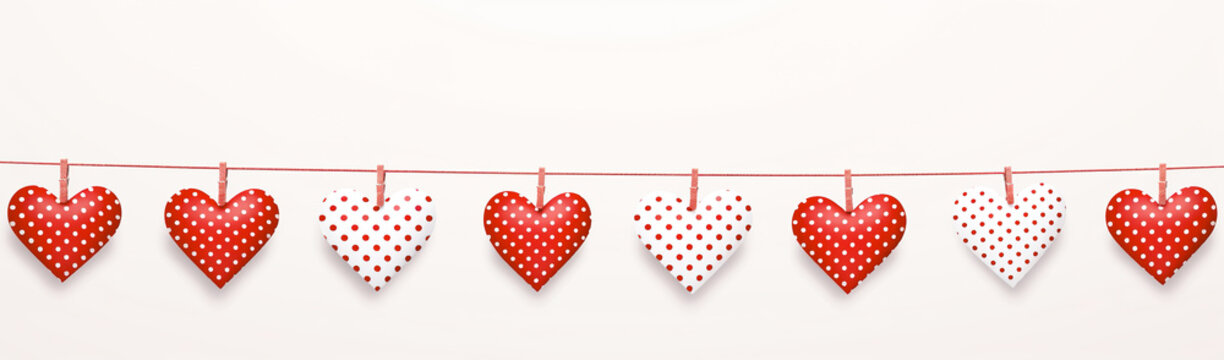 Red and white polka dots paper cuts hanging on a string over white background