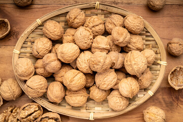 Walnuts kernels in wooden basket on wooden table.