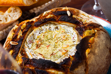 Traditional French dish of melted camembert cheese (fondue) in fresh baked bread with dried herbs...