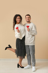 Young couple with red hearts for Valentine's day near beige wall