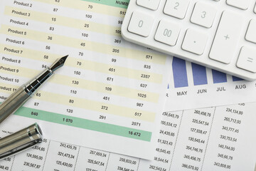 Fountain pen and calculator on accounting documents with data, top view