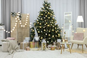 Beautiful Christmas tree, gift boxes and armchair in festive decorated room. Interior design
