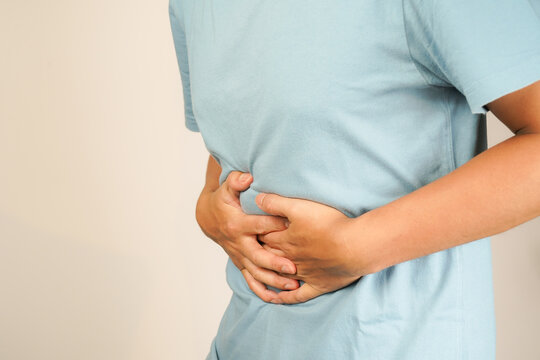 male having stomach ache, bending over and holding hands on stomach, uncomfortable due to stomach cramps, gastric pain
