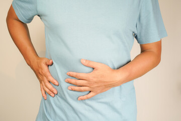 male having stomach ache, bending over and holding hands on stomach, uncomfortable due to stomach...