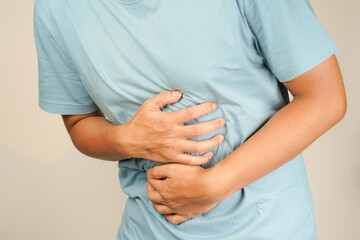 male having stomach ache, bending over and holding hands on stomach, uncomfortable due to stomach...