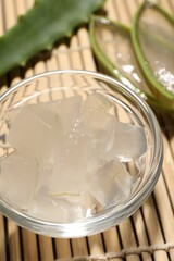 Aloe vera gel and slices of plant on bamboo mat, closeup
