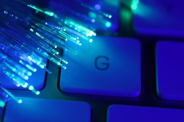 Optical fiber strands transmitting different color lights on computer keyboard, macro view