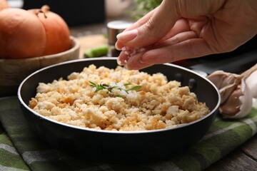 Woman salting minced chicken at wooden table, closeup