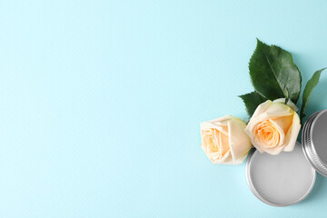 Lip balm and rose flowers on light blue background, top view. Space for text