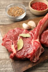 Raw ribeye steak and spices on wooden table