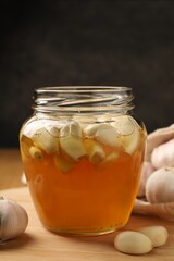 Honey with garlic in glass jar on wooden table