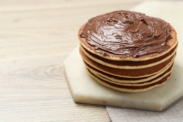 Delicious pancakes with chocolate paste on wooden table, closeup. Space for text