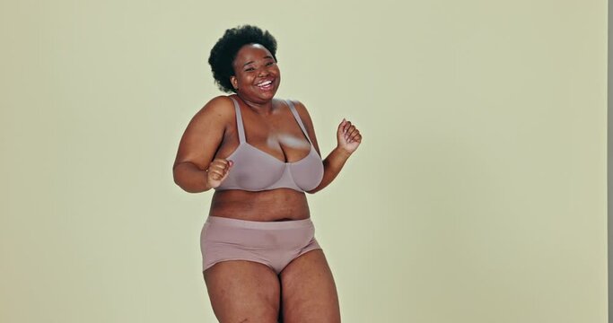 Dancing, body positivity and face of black woman in underwear in studio for self love celebration. Happy, smile and portrait of plus size young female model moving with confidence by green background