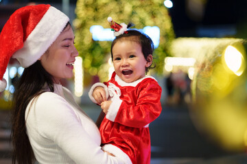 cheerful mother with daughter in santa dress and christmas light at night. happy new year eve