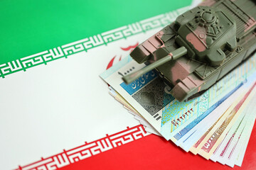 Iranian army toy tank drive on iranian bills of rial currency on flag of Islamic Republic of Iran close up