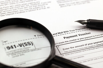 IRS Form 941-V Payment Voucher blank on A4 tablet lies on office table with pen and magnifying glass close up