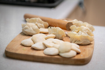 Process of making chinese dumplings. Raw dough and rolling pin on wooden chopping board.