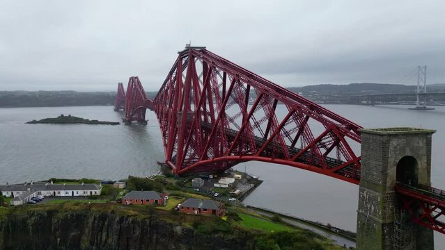The Forth rail bridge is a cantilever railway bridge across the Firth of Forth. Cinematic aerial drone shot of Forth Rail Bridge, Scotland, Forth Road bridges in background, rainy day.