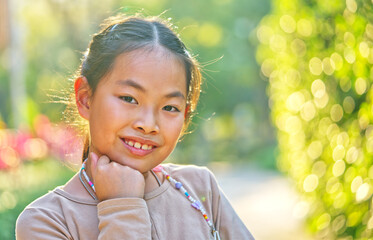Portrait Asian child girl at 9 or 10 years old in a garden, close-up portrait, smiling face, eyes...