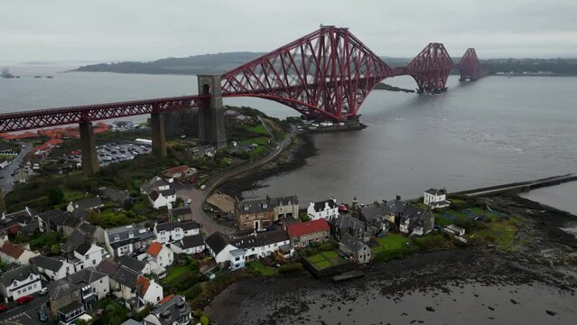 The Forth rail bridge is a cantilever railway bridge across the Firth of Forth. Cinematic aerial drone shot of Forth Rail Bridge, Scotland, Forth Road bridges in background, rainy day.