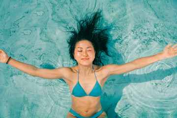 Young asian woman relaxing in the water, Beautiful girl relaxing at overwater infinity pool luxury...