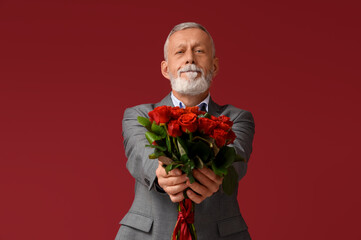 Mature man with bouquet of roses for Valentine's day on red background
