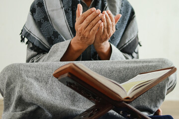 Close up muslim hands praying while sitting crossed legs on floor at mosque