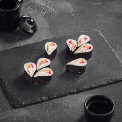 Droplet sushi roll featuring a fluffy Japanese omelet and tobiko caviar, tastefully arranged on a dark slate serving board