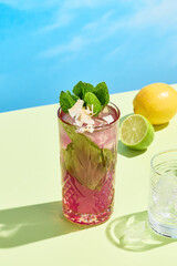 Refreshing coconut-currant lemonade with mint, served in a  glass against a sunny blue backdrop