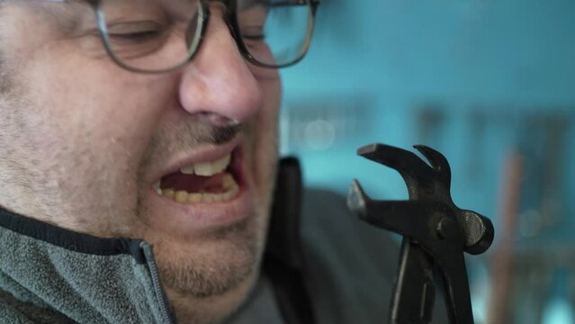 Scared Man Afraid to Pull a Teeth Out Using a Plier Closeup