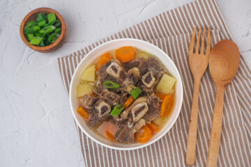 Sop Iga (Beef ribs soup) made from ribs, carrots, potato and leeks. Served in white bowl. Indonesian food.