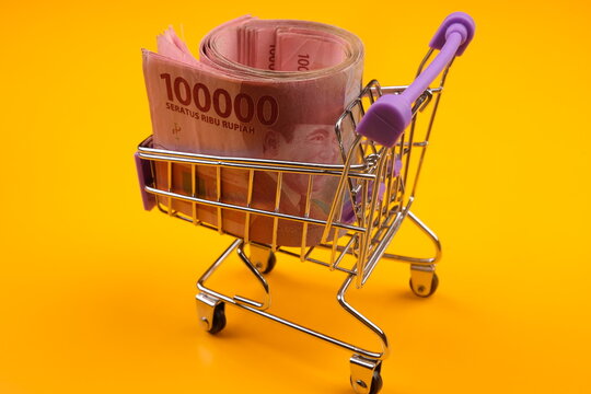 Shopping cart full of money (Indonesian Rupiahs). Multi currency basket concept. IDR. Seratus ribs rupiah. One hundred thousand rupiah. Economy concept. Indonesia currency. 