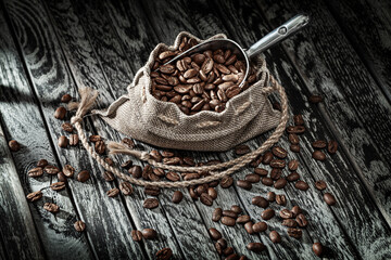Coffee Beans In Burlap Bag And Scoop On Vintage Wood.