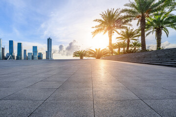 Empty square floor and green palm trees with modern city buildings scenery at sunset