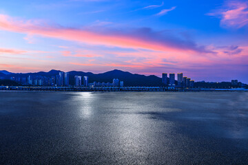 Fototapeta premium Asphalt road and residential area buildings with mountain scenery at sunset