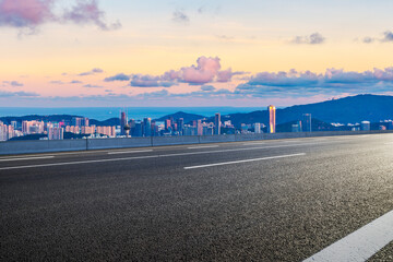 Asphalt highway road and city skyline with modern buildings at sunset by the sea. high angle view.