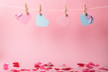 Paper pink and blue hearts on clothespins on a pink background. DIY holidays. Copy space.