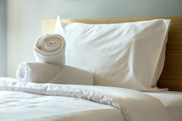 Soft pillows and white towel on clean white bed. Pillows bed with bedding sheets in bedroom. Bed sheets and pillows messed. Hotel, resort or home can relax on bed for deep sleep. - obrazy, fototapety, plakaty