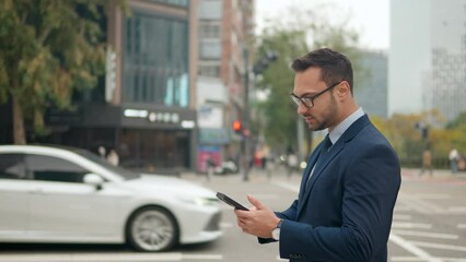 Businessman Holding Phone While Standing On The Sidewalk With Traffic In The Background In Seoul, South Korea. - medium shot