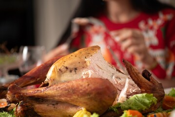 Turkey dinner Thanksgiving food. Man carry Christmas turkey food dinner Serve on table. Baked turkey chicken garnished with family Christmas tree and burning candles . Roasted turkey table setting