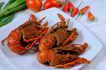 fried lobster on a white ceramic plate. seafood. crustacean. lobster goreng. blurred image. 