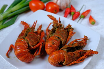 fried lobster on a white ceramic plate. seafood. crustacean. lobster goreng.